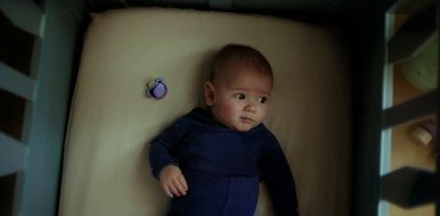 a baby laying in a crib looking at the camera