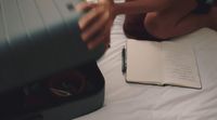 a person laying on a bed with a book and a pen