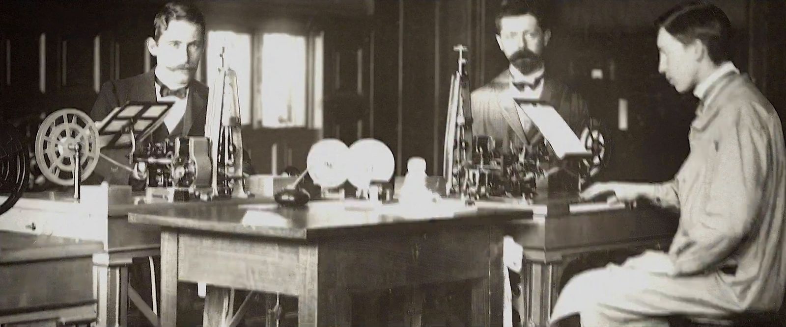 a black and white photo of two men sitting at a desk