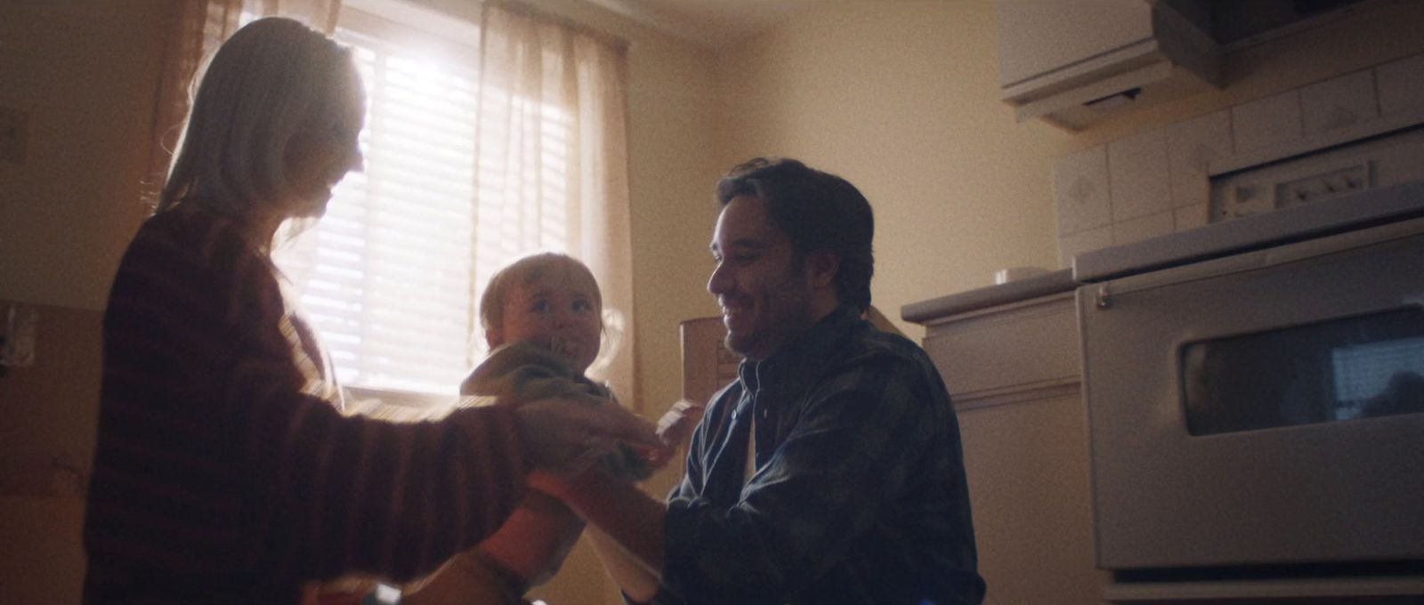 a man and a woman holding a child in a kitchen