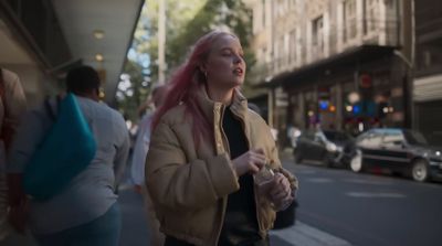 a woman with pink hair walking down the street