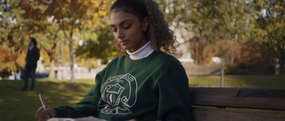a woman sitting on a bench writing on a piece of paper