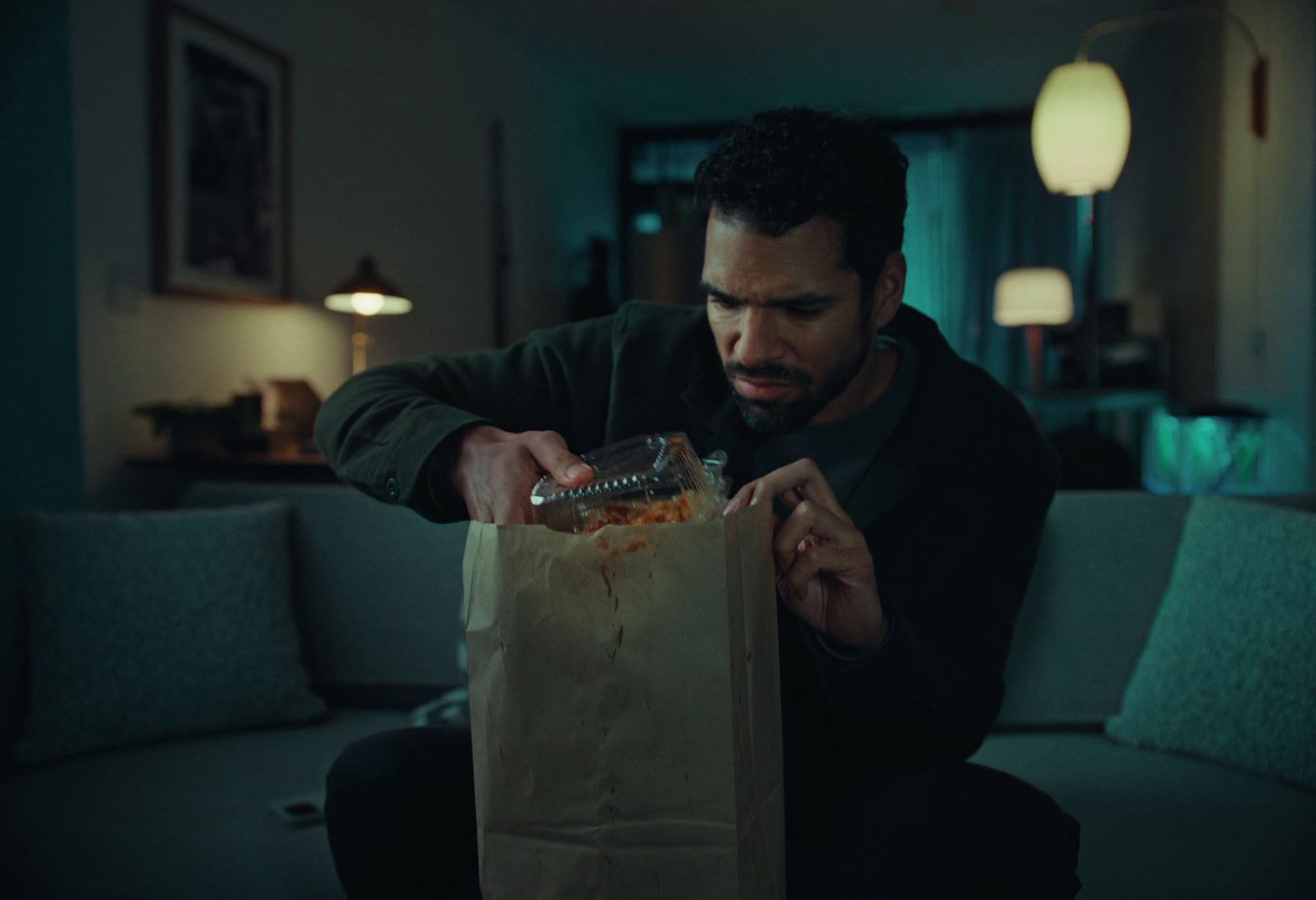 a man sitting on a couch holding a bag of food