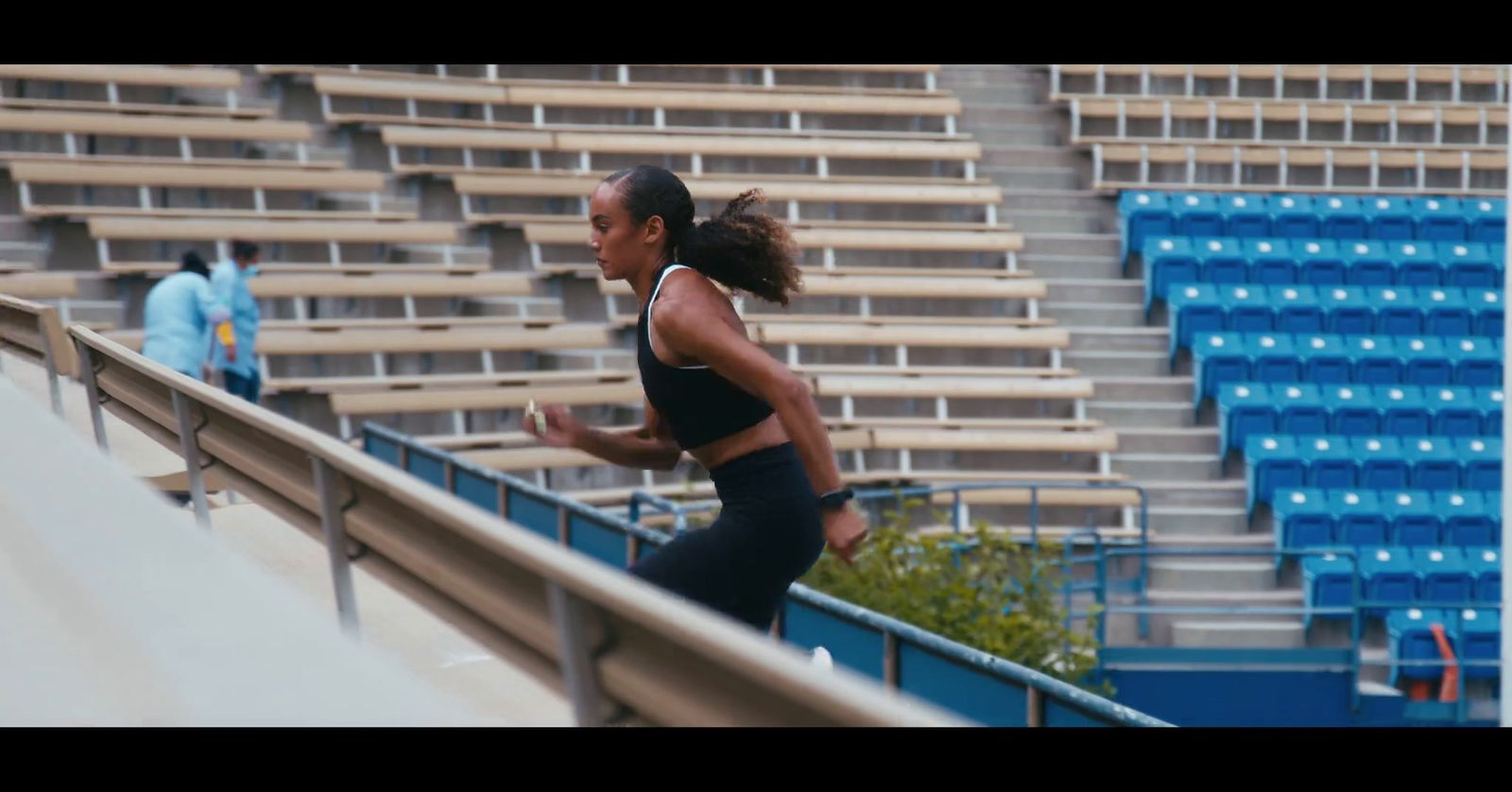 a woman running down a track in a stadium