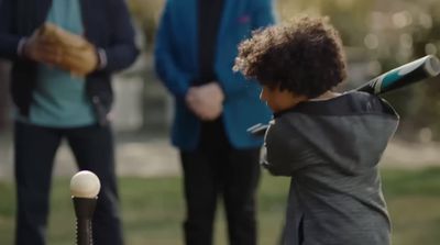 a young boy swinging a baseball bat at a ball