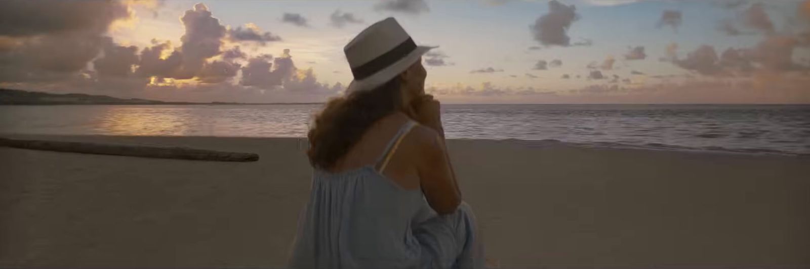 a woman wearing a hat standing on a beach