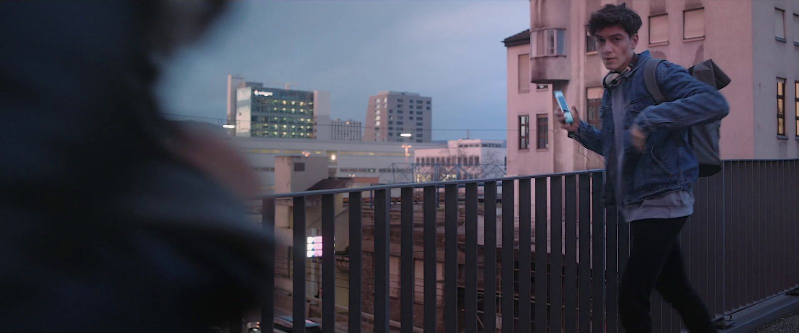 a man standing on a balcony looking at his cell phone