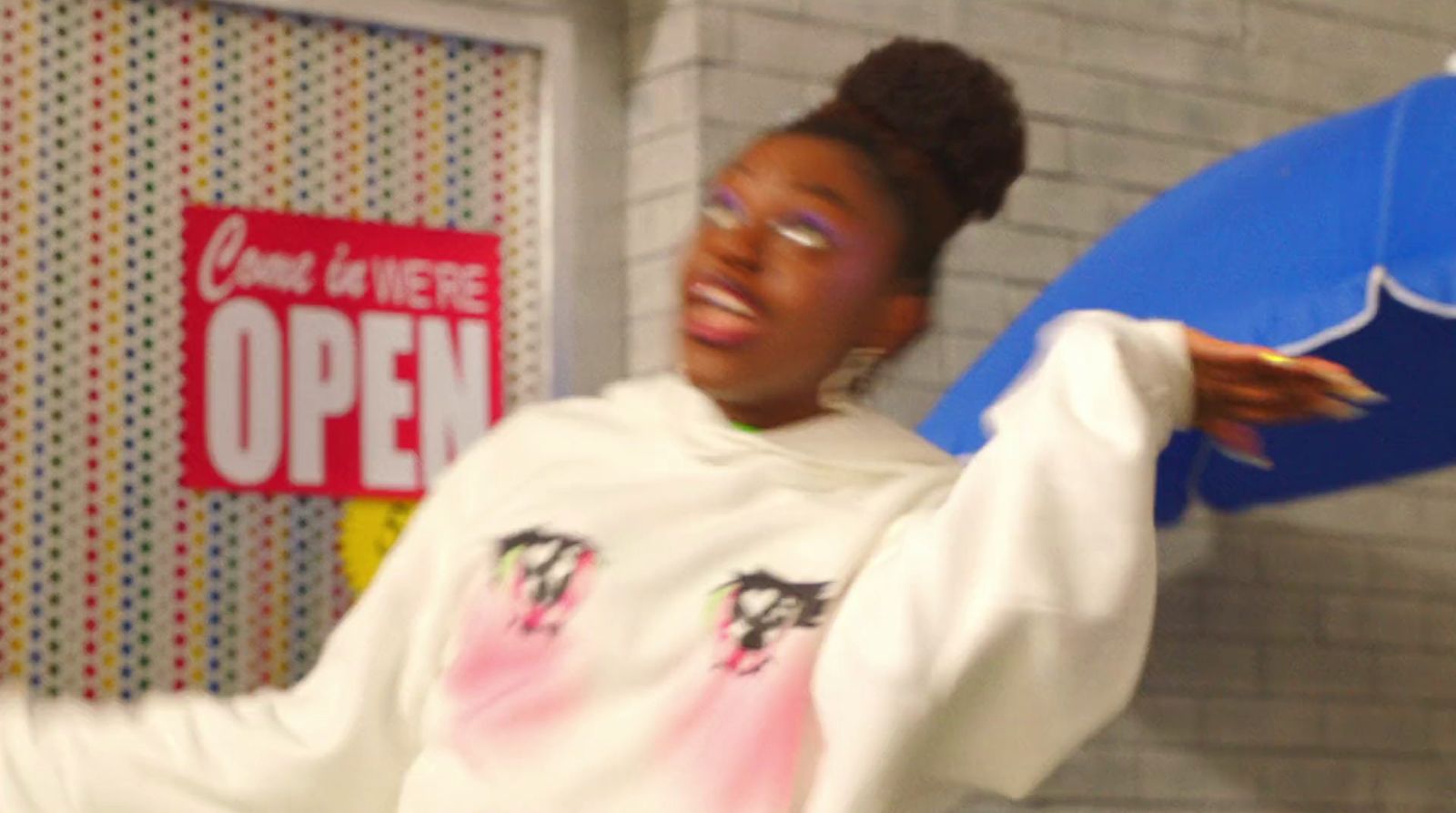 a woman in a white sweatshirt holding a blue surfboard