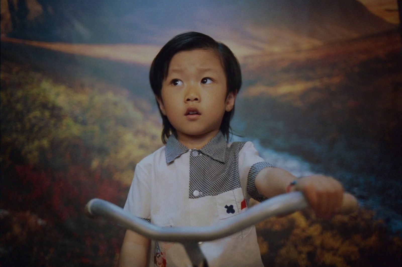 a little girl holding a bike in front of a picture