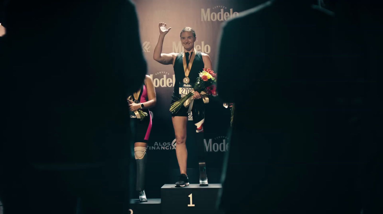 a woman standing on top of a podium holding a bouquet of flowers