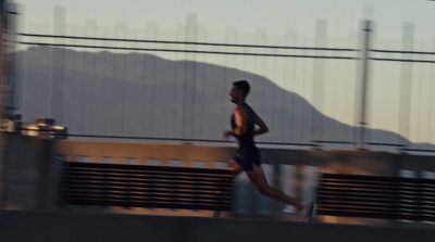 a man running across a bridge with mountains in the background