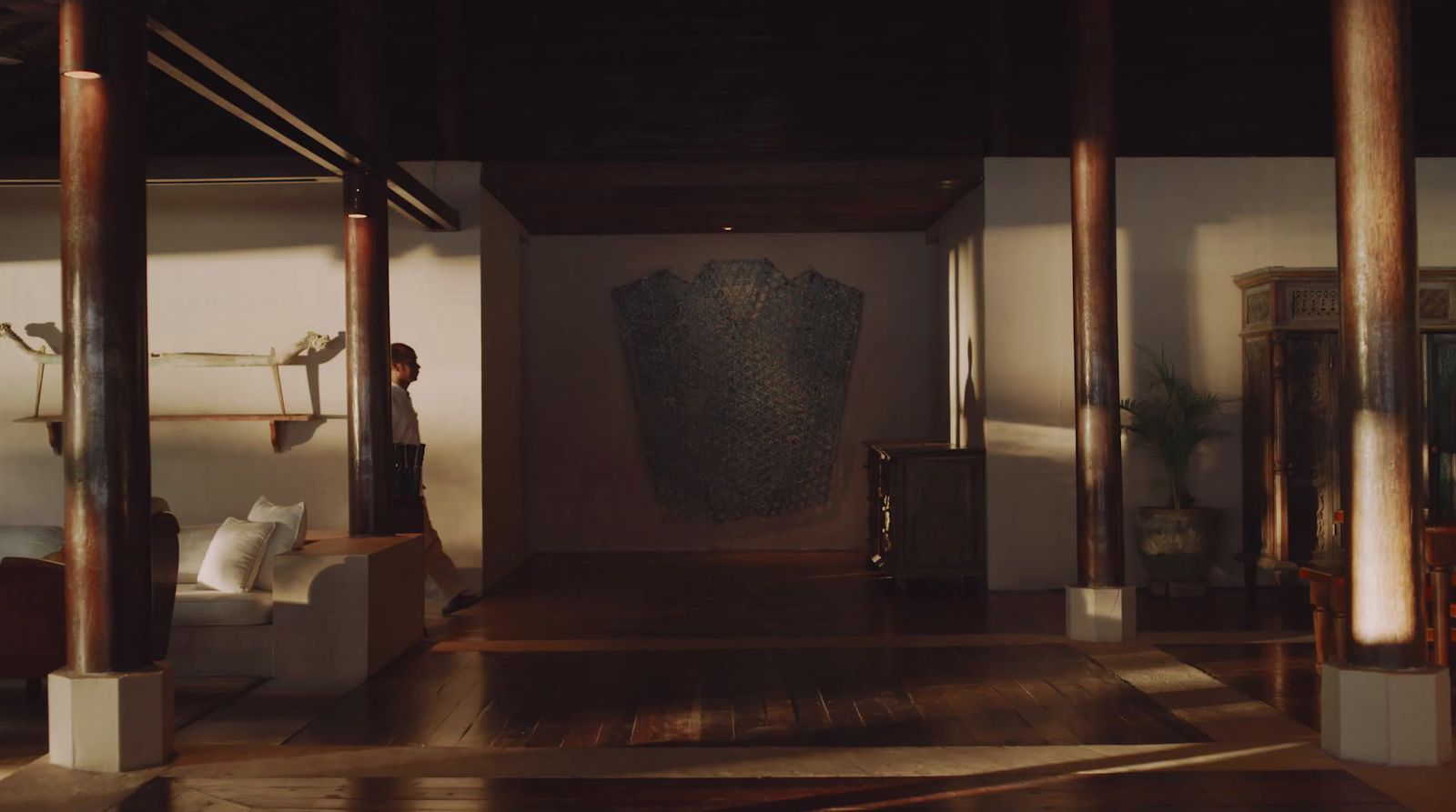 a person standing in a room with a large vase on the wall