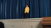 a woman standing on a stage in front of a blue curtain