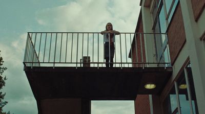 a woman standing on a balcony with a suitcase