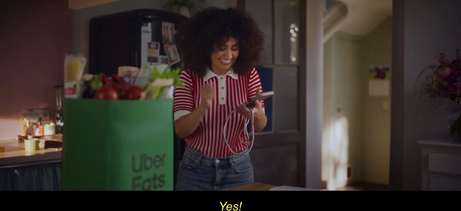 a woman standing in a kitchen holding a cell phone