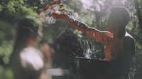 a woman holding a bucket of water in a forest