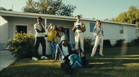 a group of people standing and sitting in front of a house