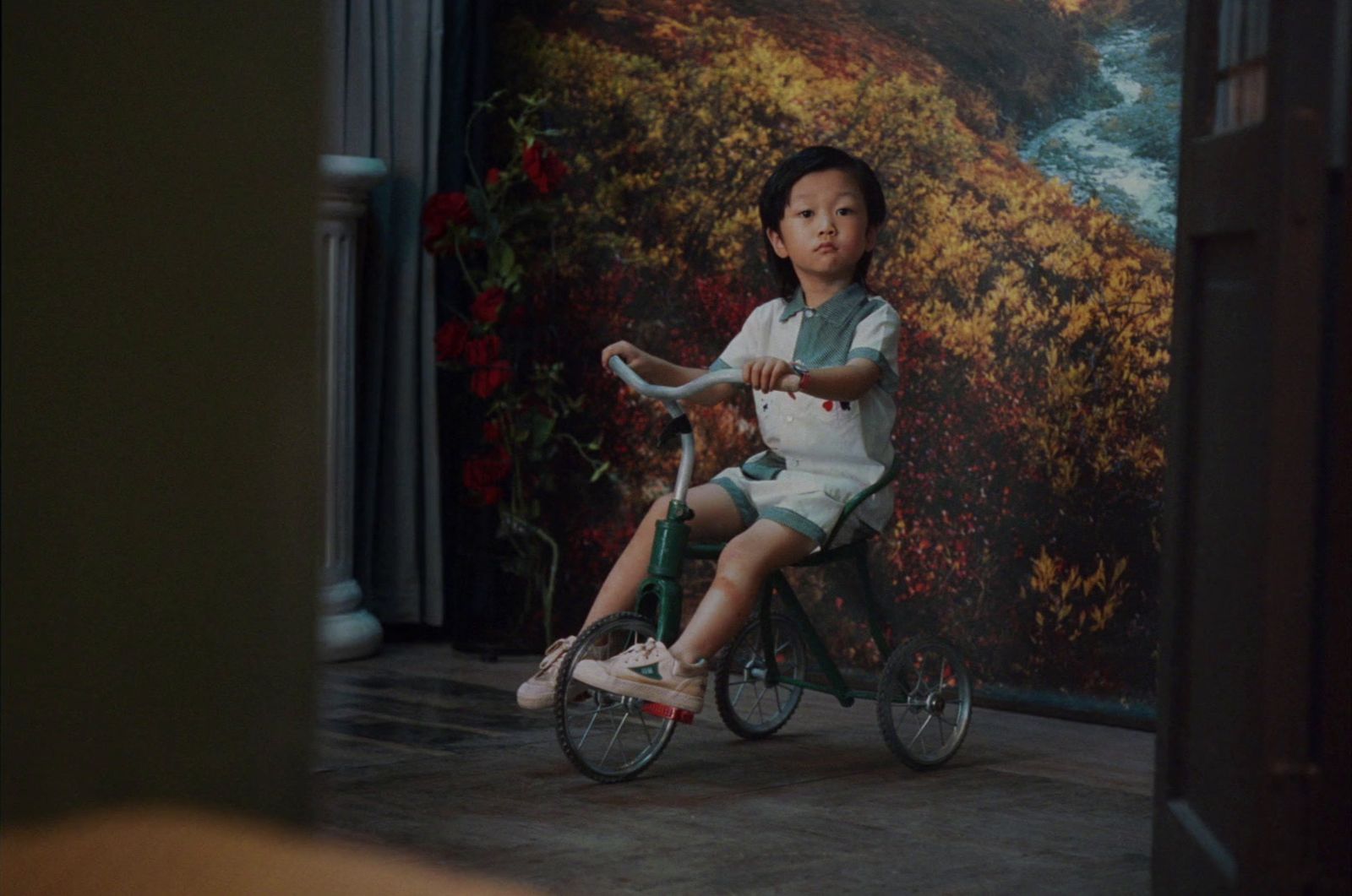 a little girl riding a bike in front of a painting