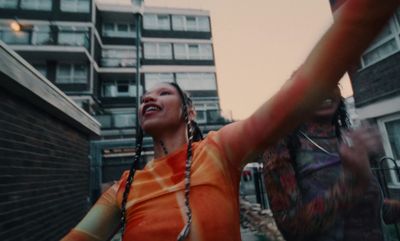 a woman in an orange shirt is dancing in the street