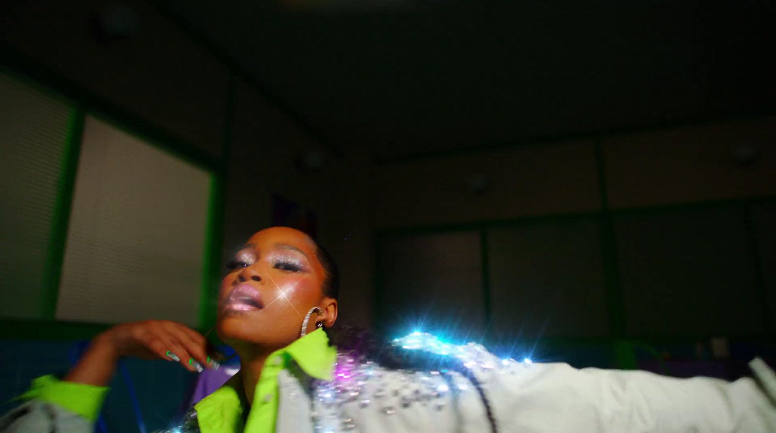 a woman wearing a neon green jacket and a pair of earrings