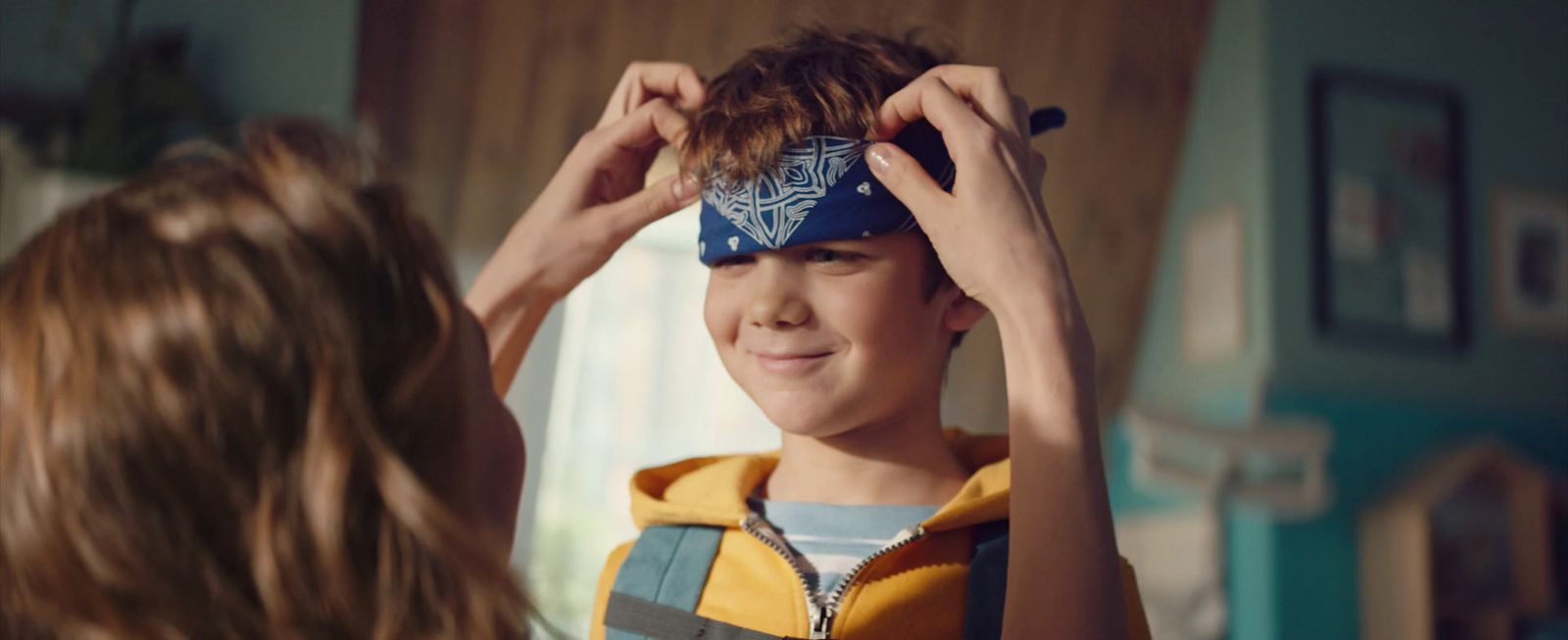 a young boy is putting on a hat