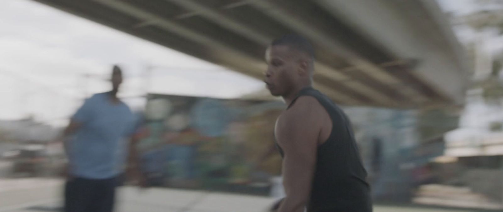 a blurry photo of two men walking under a bridge