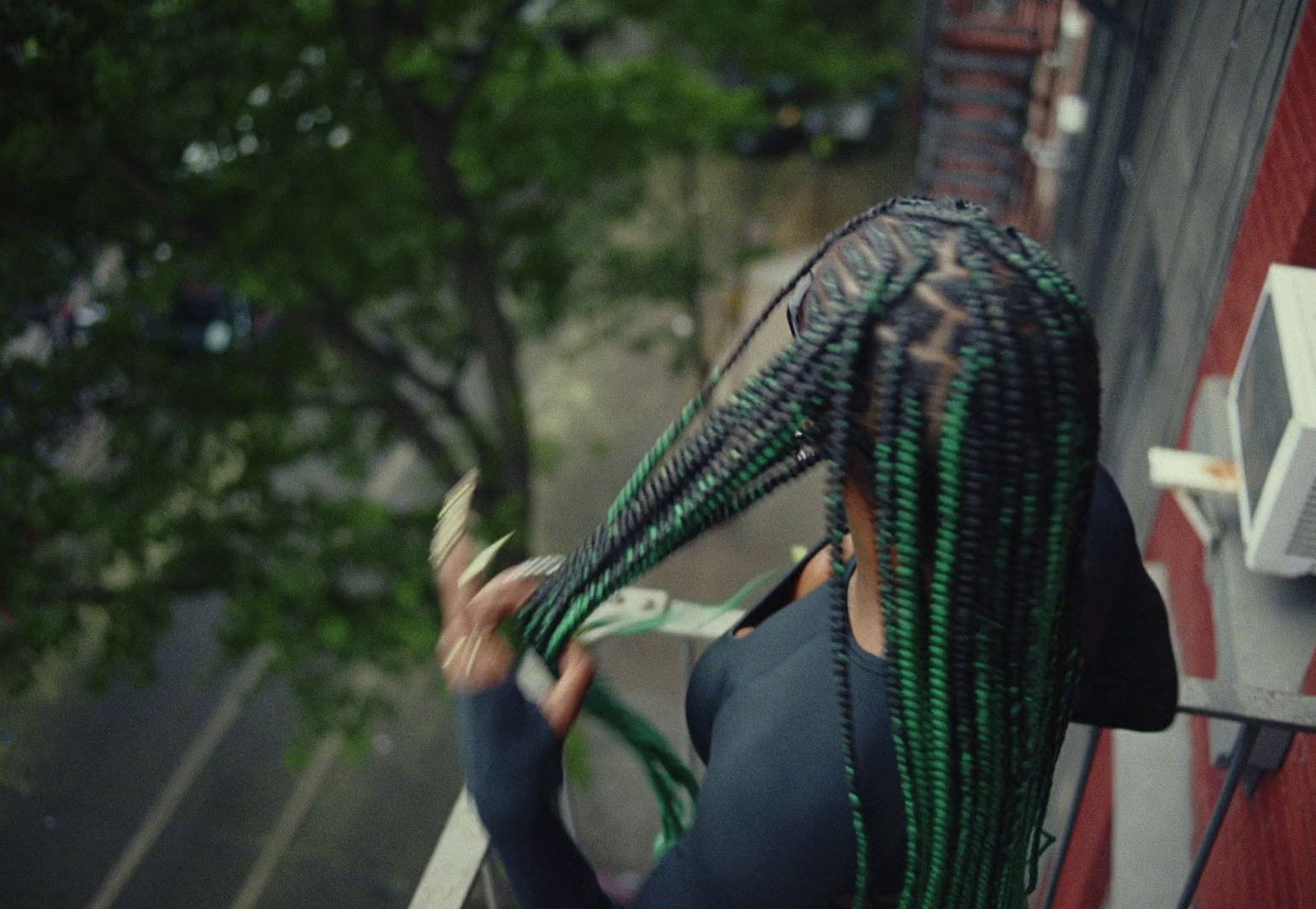 a woman with green and black dreadlocks on her head