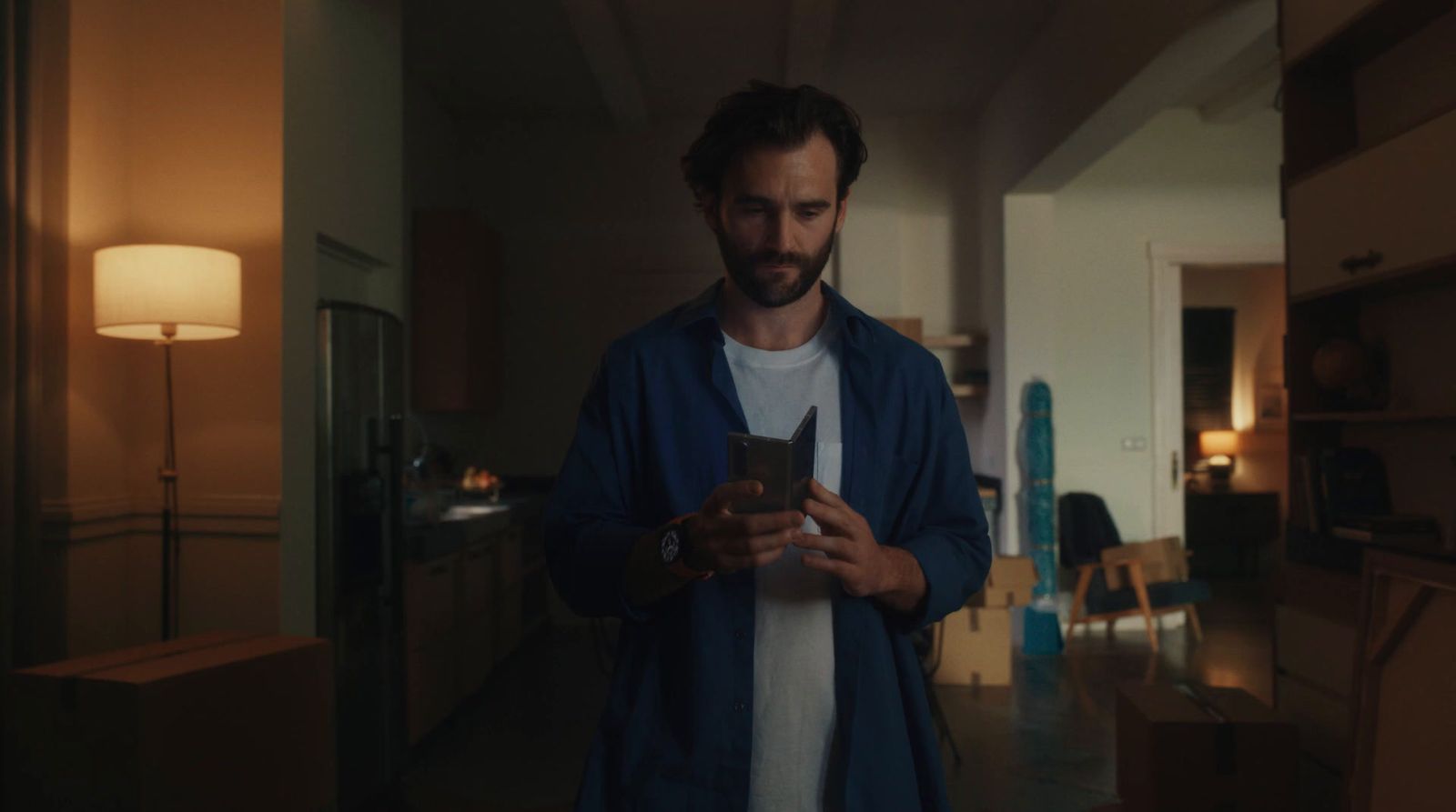 a man standing in a room looking at a cell phone