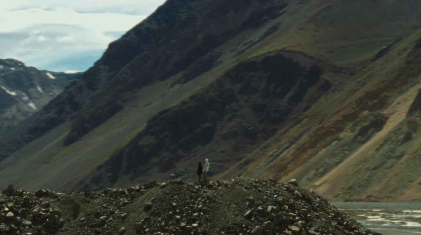 a man standing on top of a mountain next to a river