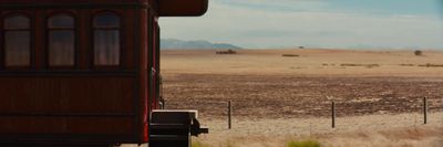 a train traveling through a desert with mountains in the background