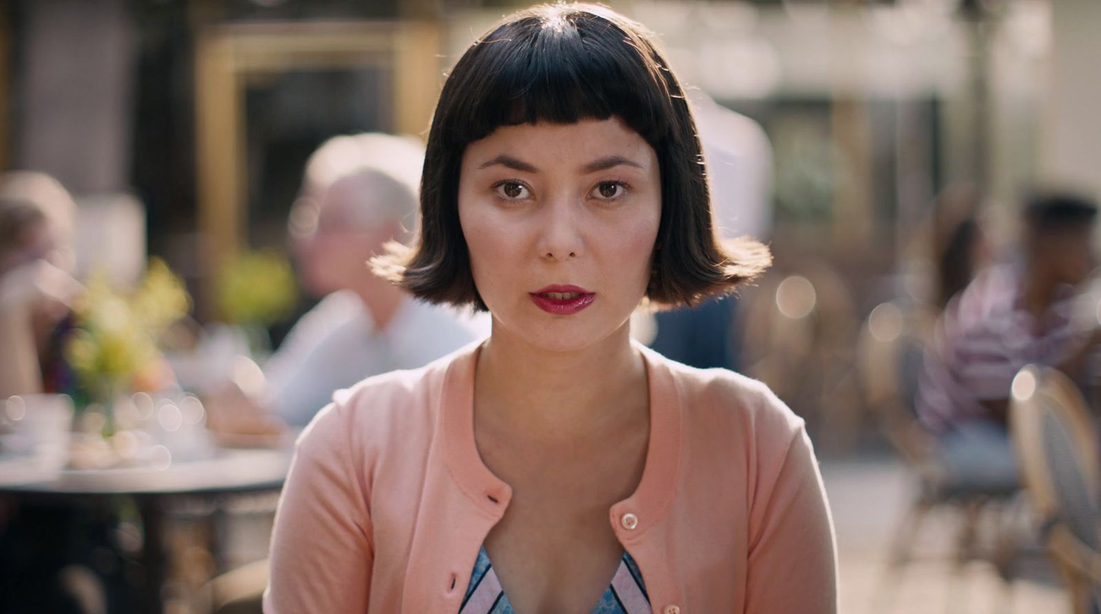 a woman in a pink jacket sitting at a table