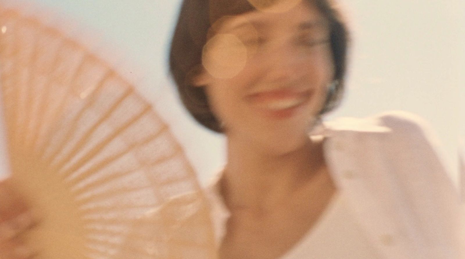 a woman is holding a fan and smiling