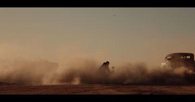 a truck driving down a dirt road next to a truck