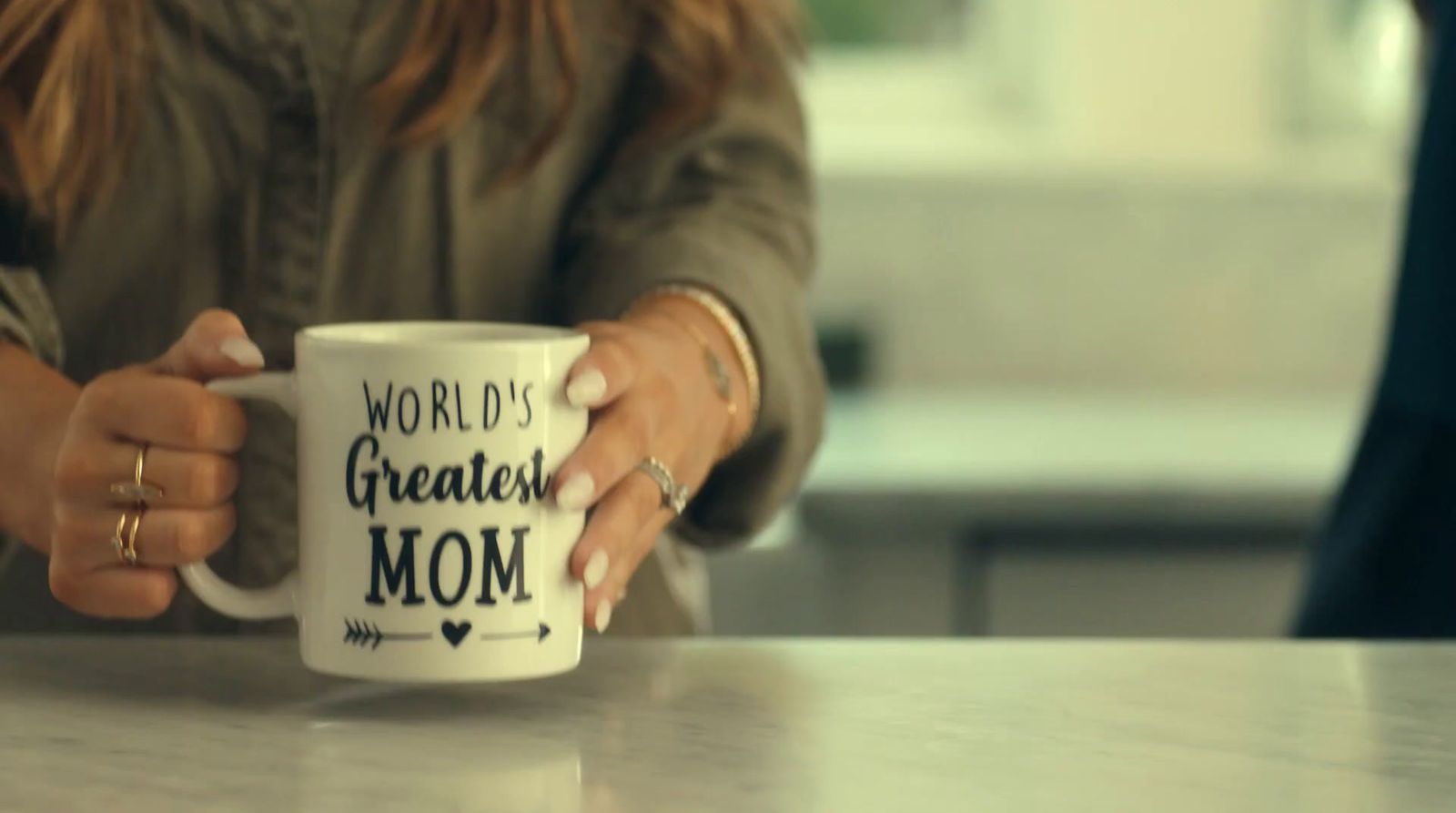 a woman holding a coffee mug with the words world's greatest mom on it