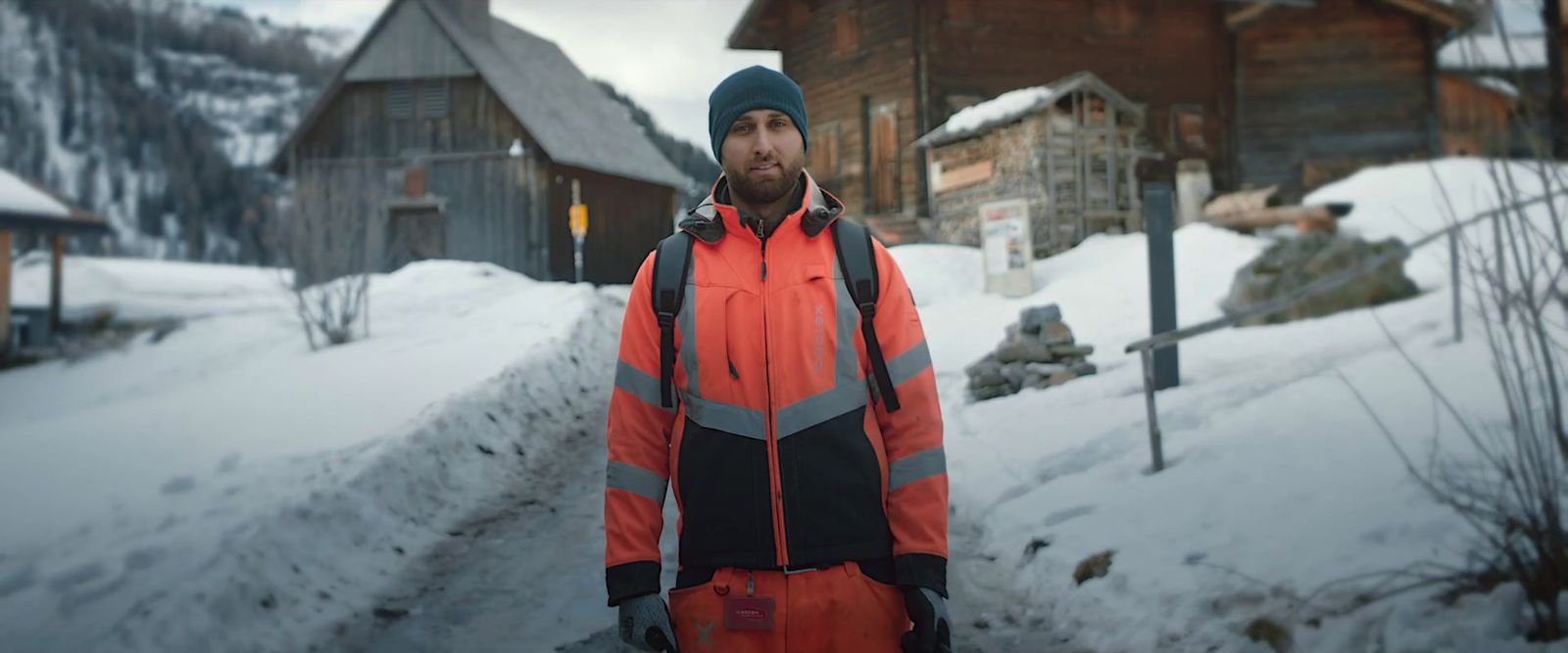 a man in an orange and black jacket standing in the snow