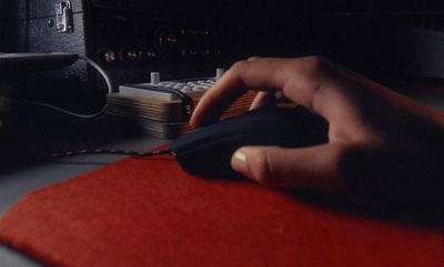 a person's hand on a mouse pad in front of a computer