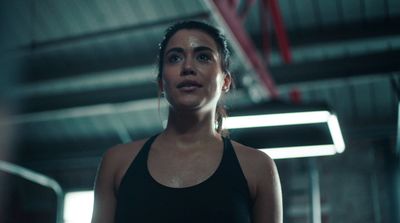 a woman in a black tank top standing in a gym