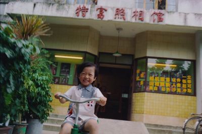 a young child riding a scooter in front of a building