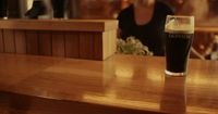 a woman sitting at a bar with a glass of beer