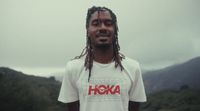 a man with dreadlocks standing in front of a mountain