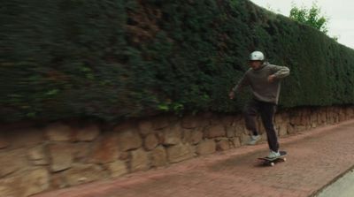 a man riding a skateboard down a sidewalk