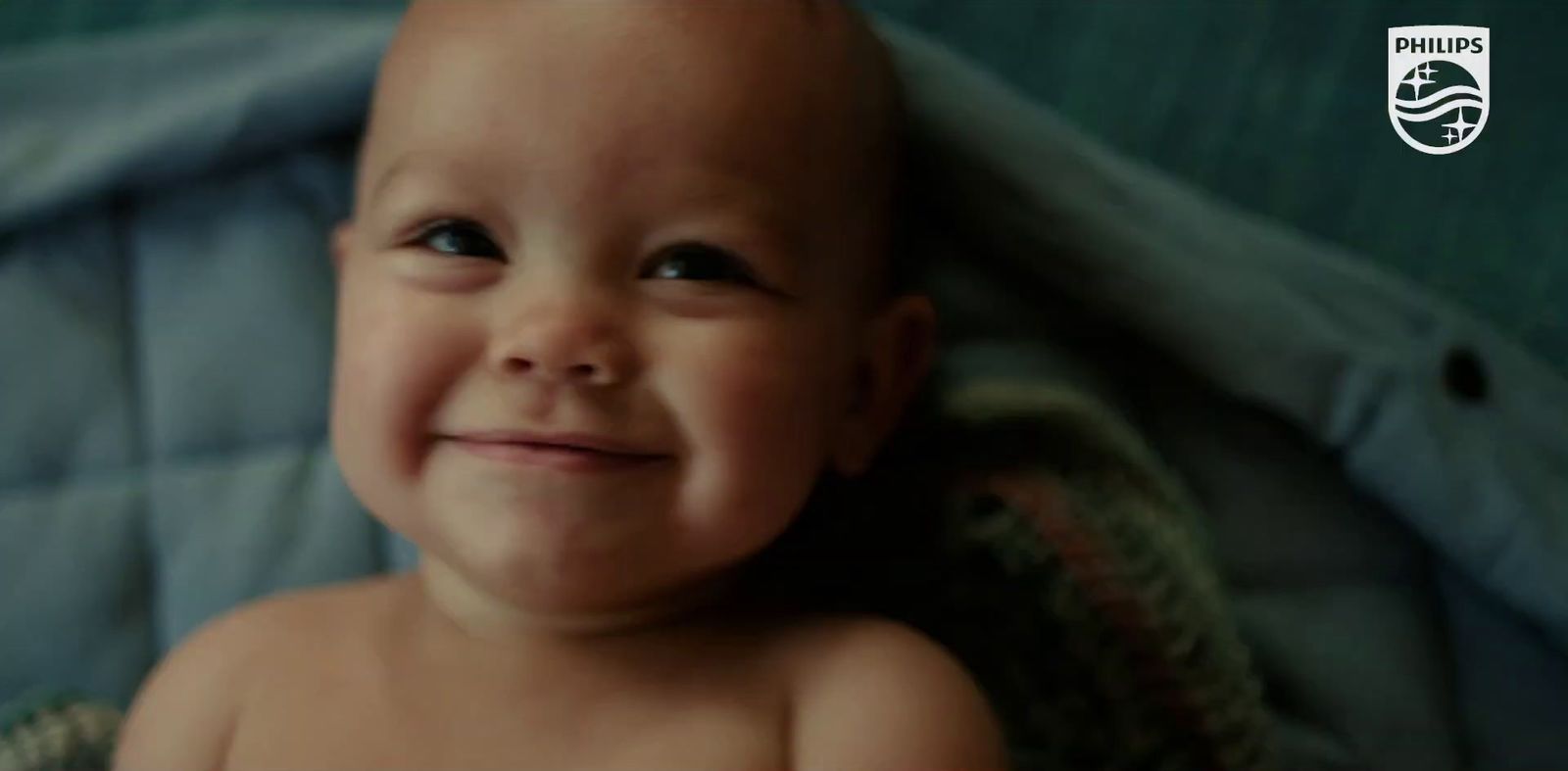 a smiling baby sitting on top of a blanket