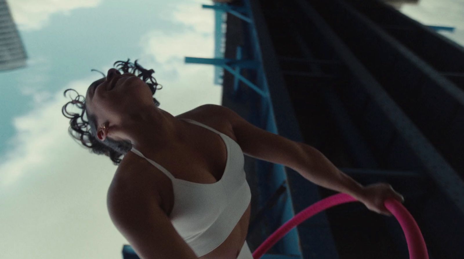 a woman in a white tank top holding a pink hula hoop