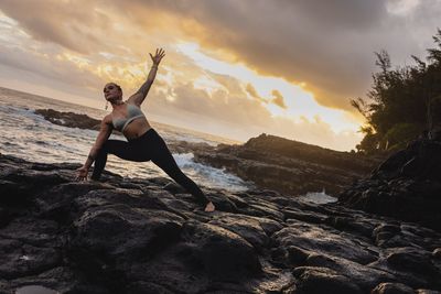 a woman doing yoga on a rocky beach