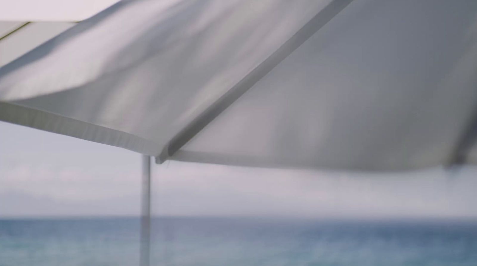 a white umbrella sitting on top of a sandy beach