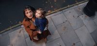 a woman holding a small child on top of a sidewalk