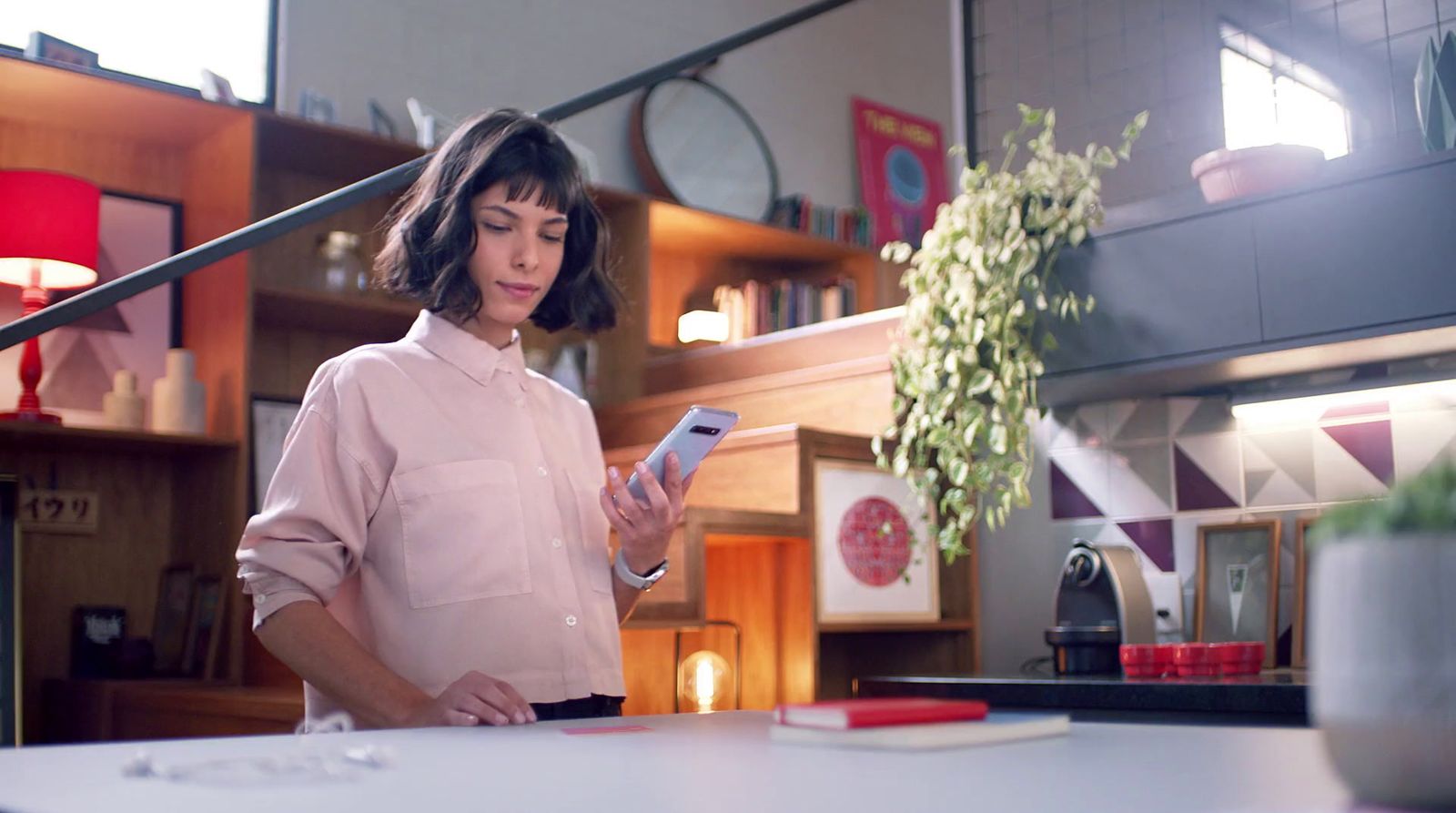 a woman standing in a kitchen looking at a cell phone