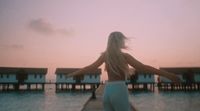 a woman standing on a dock in front of a body of water