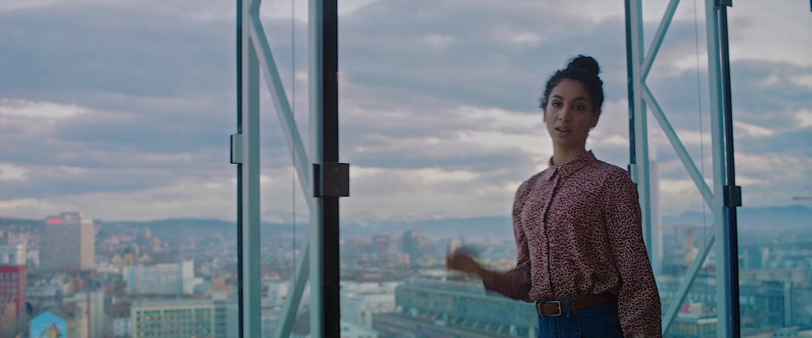 a woman standing in front of a window with a view of a city