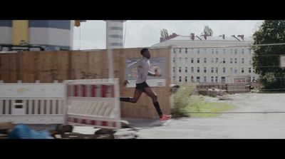 a man running down a street next to a fence